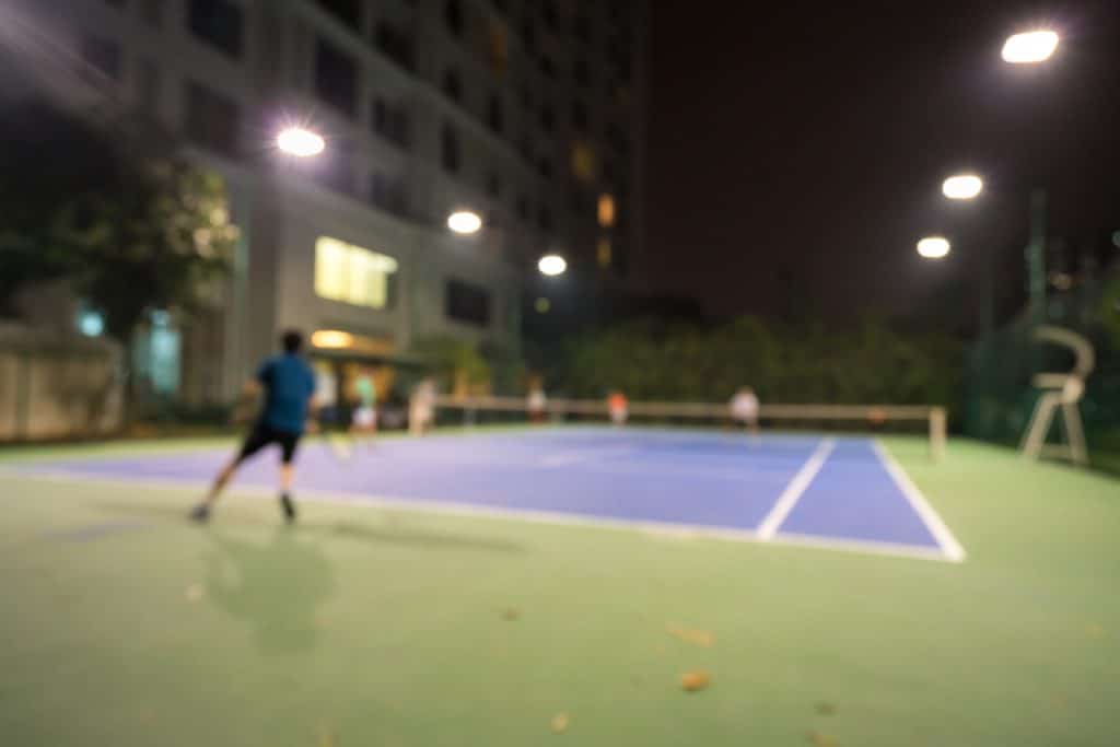 Blurred tennis court in the night with apartment building on background in city